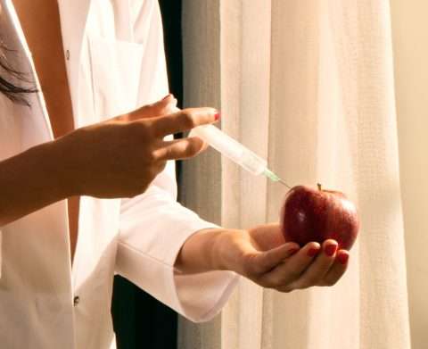 Frau mit Spritze und Apfel in den Händen am Fenster