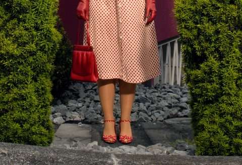 Frau mit rot gepunktetem Kleid und roter Tasche.