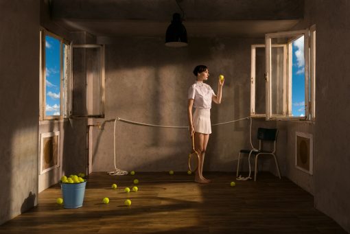 Die Fotografie von Horst Kistner Late Morning aus dem Jahr 2022 gehört zum Zyklus One Day in June. Eine Tennis spielende Frau in einem Zimmer zielt mit dem Ball auf das Fenster.