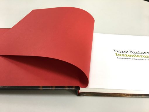Horst Kistner Katalog Inszenierungen hat ein edles, rotes Vorsatzpapier und ist handwerklich mit Faden gebunden.