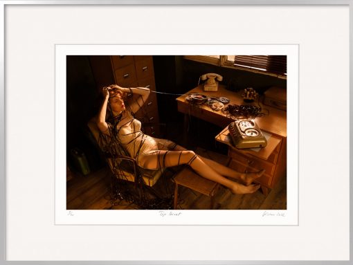 Die Fine Art Fotografie von Horst Kistner mit dem Titel Top Secret zeigt eine Frau im Büro. Sie ist lediglich mit einem Mieder bekleidet und schein verzweifelt zu sein.