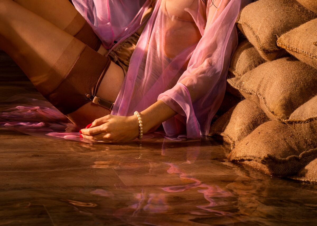 Dieses hocherotische Detail der inszenierten Fotografie von Horst Kistner mit dem Titel After The Flood zeigt die Strapse der im Wasser sitzenden Frau.