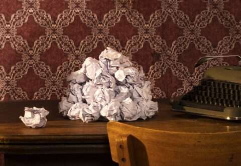 Dieses Detail der Fotografie von Horst Kistner The Paper Rose zeigt einen Haufen zerknülltes Papier auf dem Tisch vor einer Schreibmaschine.