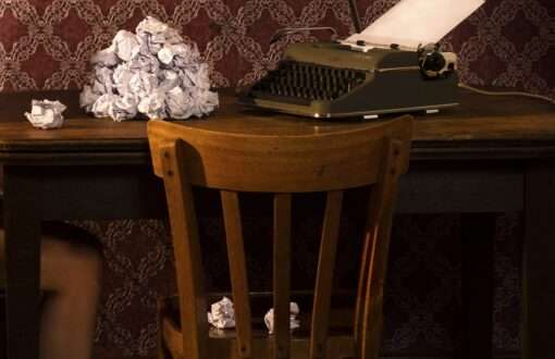 Das Detail der Fotografie von Horst Kistner The Paper Rose zeigt den Stuhl auf dem zerknülltes Papier liegt und die Schreibmaschine auf dem Tisch.