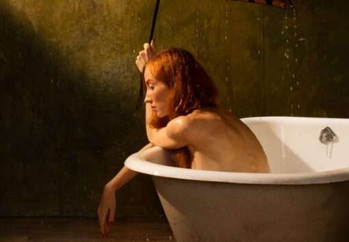 Horst Kistner Monsun Fotografie zeigt im Detail 1 die nackte Frau in der Badewanne. Es regnet in den Raum. Sie hält einen Schirm über sich.