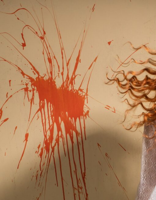 Dieses Detail von Horst Kistner Twister Fotografie zeigt die verspritzte orange Farbe auf der Wand hinter der wild tanzenden Frau im Vintage Stil.