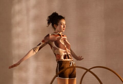 Detail aus ‚Hoop‘ von Horst Kistner: Oberkörper der Tänzerin im Retro-Shirt, beleuchtet von warmem Seitenlicht.