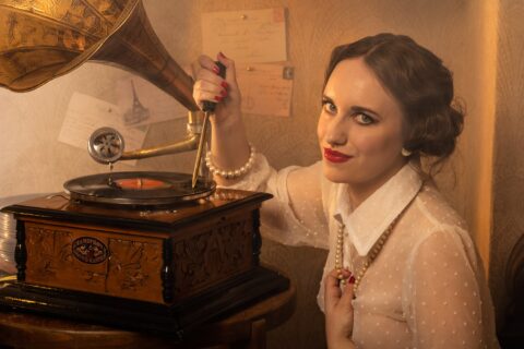 Diese Frau mit blutroten Lippen und einer Perlenkette blickt schelmisch in die Kamera, während sie mit einem Dorn in eine Schallplatte sticht. Dies ist eine typisch surreale Fotografie mit dem Titel La Gravure von Horst Kistner. Ein Sinnbild für böse Frauen in der Kunst, verführerisch, intelligent und ironisch – eine originelle Kunstfotografie und außergewöhnliche Geschenkidee oder Geburtstagsgeschenk für Frauen mit Stil.